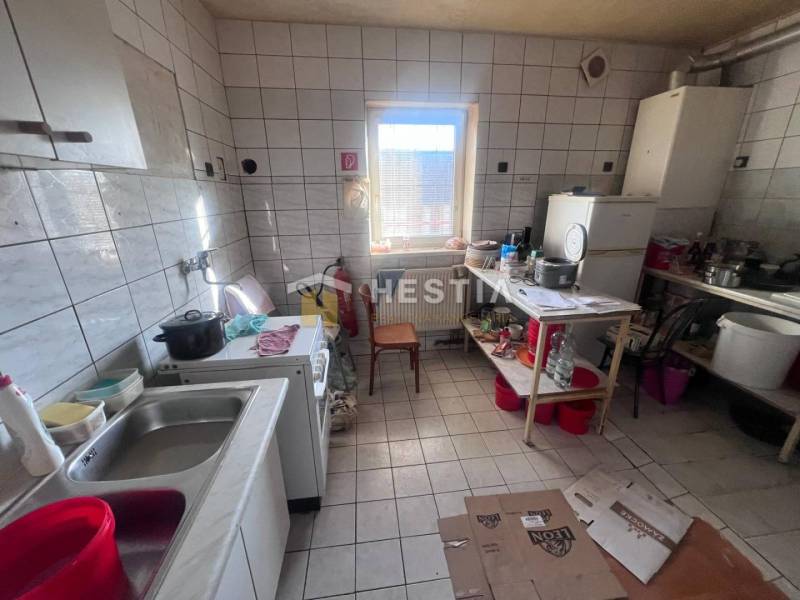 A kitchen with a tiled floor, a stove, and dishes on the shelf, catering spaces.