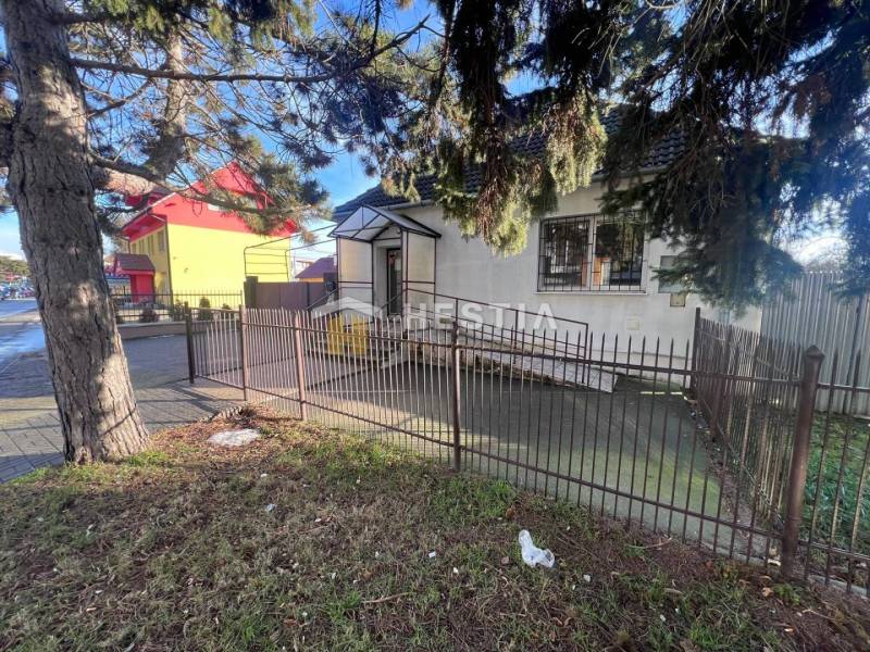 An older house surrounded by a fence and trees near dining spaces in Senica.