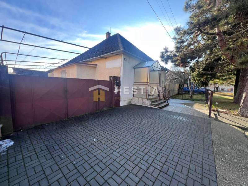 Family house with a garden in Senica, large entrance gate, paved courtyard, tree.