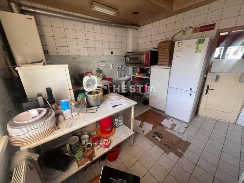 Kitchen with gastro spaces, white tiles, dispensers, kitchen utensils, fan, refrigerators.