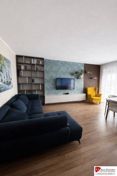 Living room with a blue sofa, a yellow armchair, and a wooden decor floor in a three-room apartment.