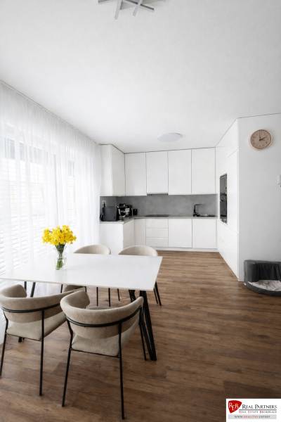 Dining table with chairs and a kitchen in a 3-room apartment with a wooden decor floor.