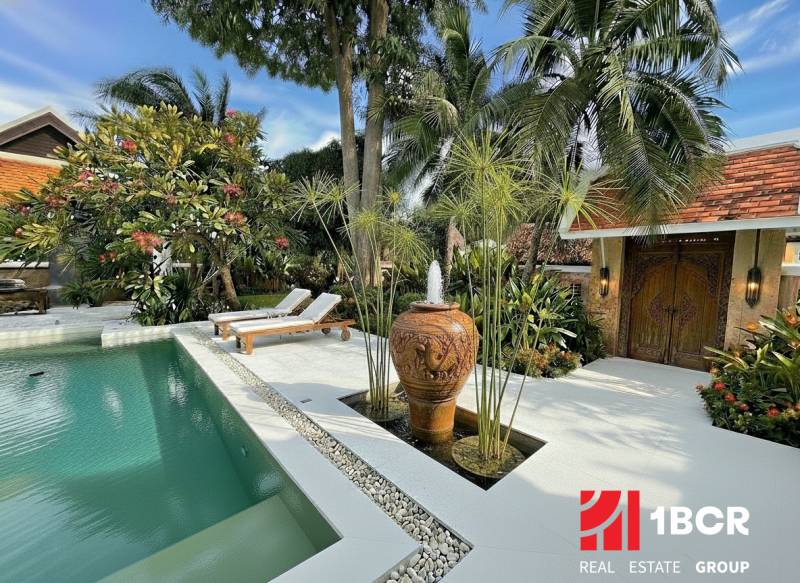 A view of a luxury villa in Pattaya with a pool and exotic garden.