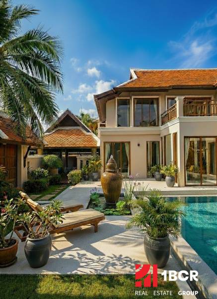 Villa in Pattaya with a pool, wooden decor, and a garden with palm trees and loungers.