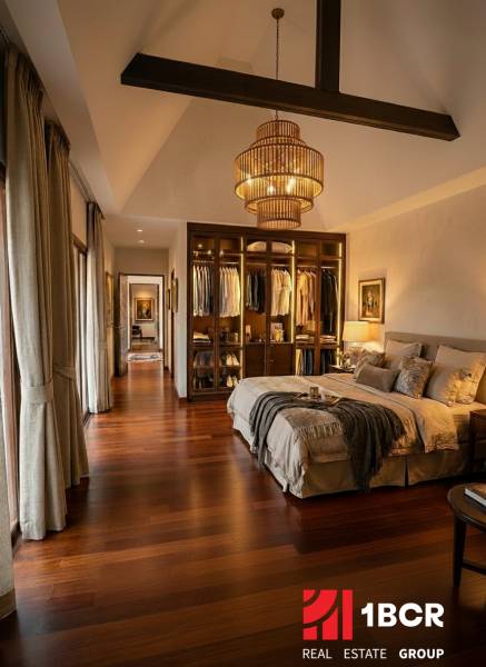 Stylish bedroom in a villa with wood-patterned flooring and an open wardrobe.