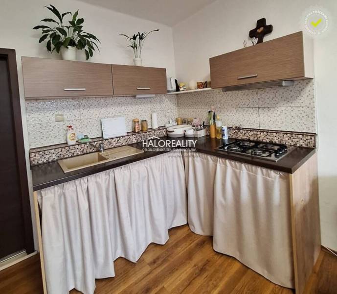 A kitchen in a 3-room apartment with a wooden decor floor and a gas stove.