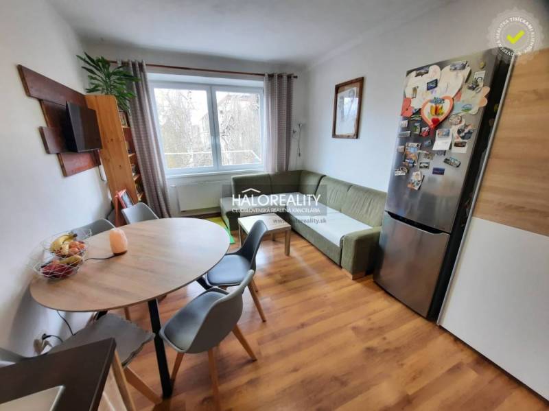 Living area in a 3-room apartment with a wood-patterned floor and a dining table.