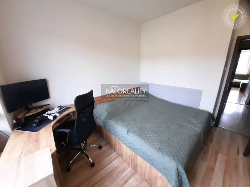 A bedroom with a desk and wooden decor flooring in a 3-room apartment.