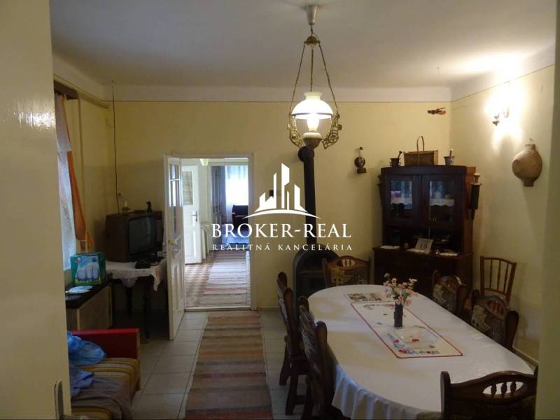 Dining room in a family house with wooden furniture, a television, and an entrance to another room.