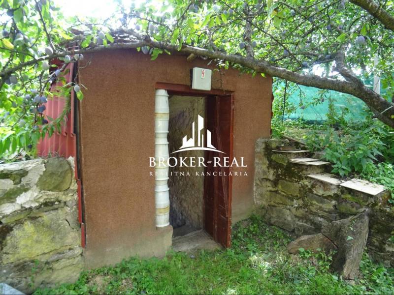A small garden shelter next to a stone wall in the garden of the Goncruszka family house.