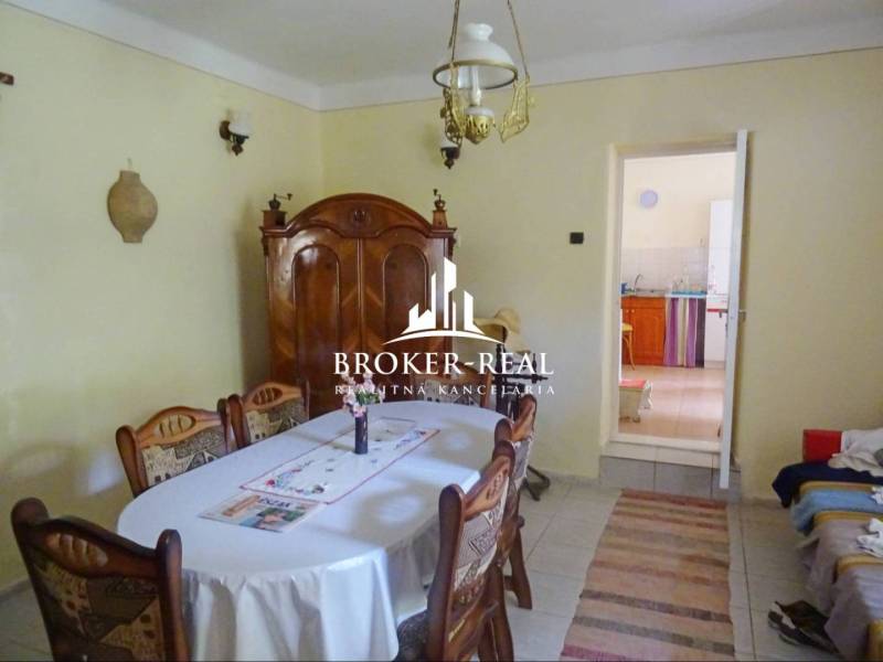 A dining room in a family house with wooden furniture, a table, chairs, and a ceiling lamp.