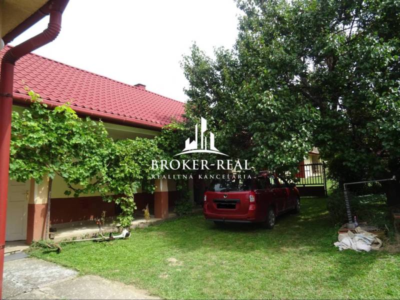 The garden of the family house in Goncruszka with a red roof and a car on the lawn.