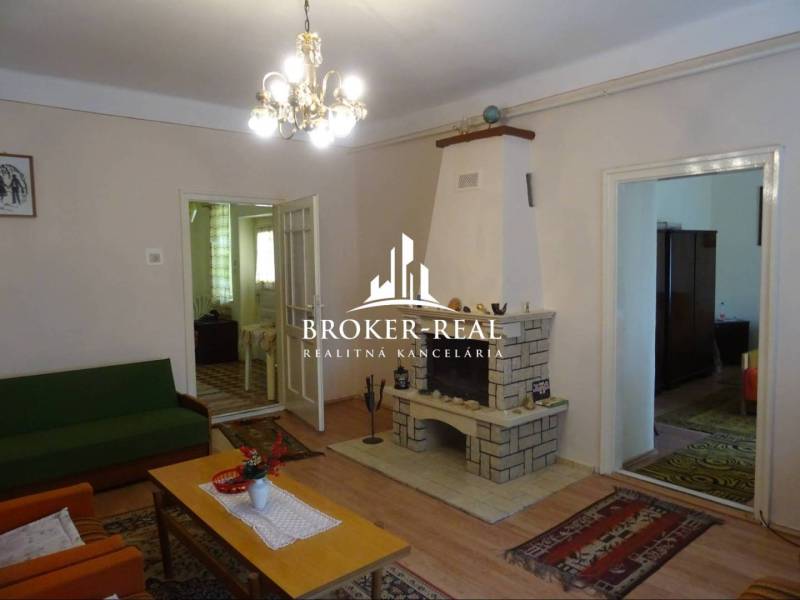 Living room in a family house with a fireplace, wood-patterned flooring, and a chandelier.