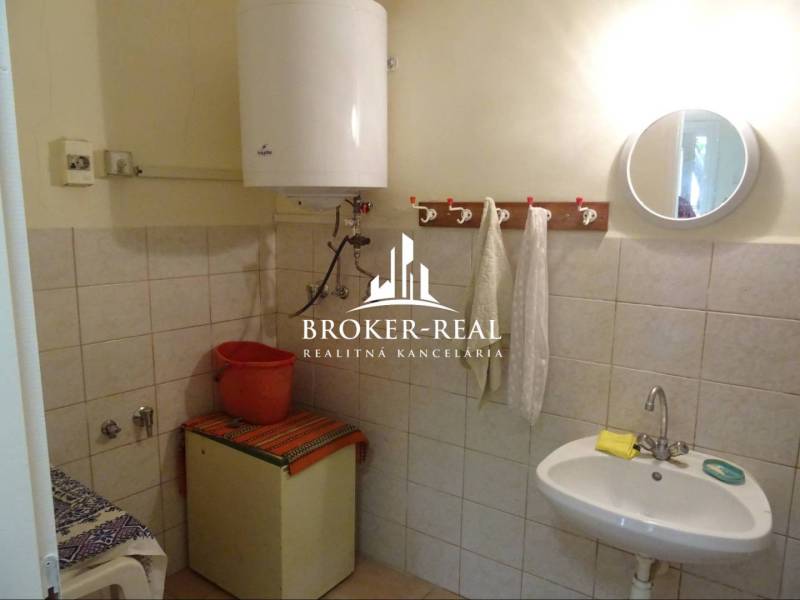 Bathroom with tiles, sink, water heater, and mirror in a family house.
