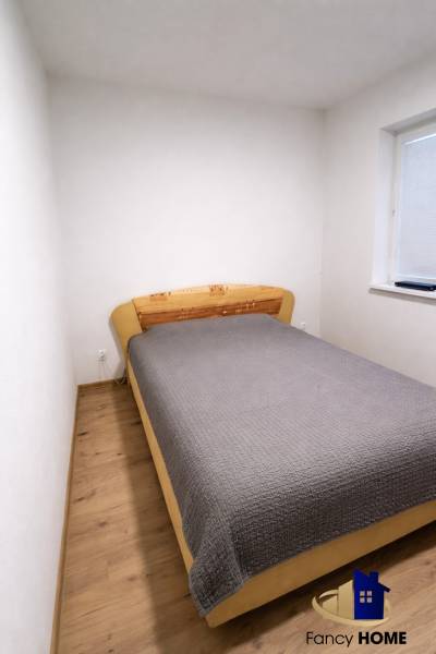 Bedroom in a 2-room apartment with a bed and a floor with a wooden decor.