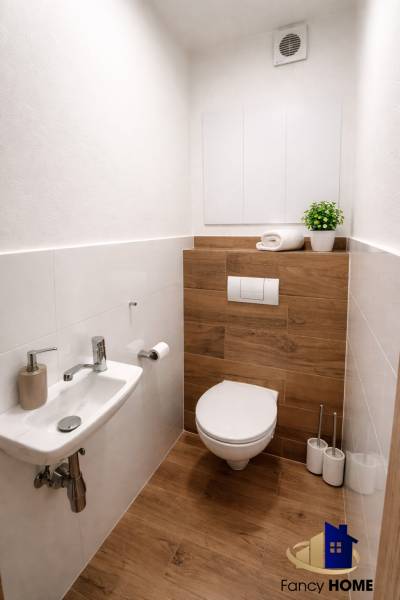 A bathroom in a 2-room apartment with a wooden decor floor and a simple sink.