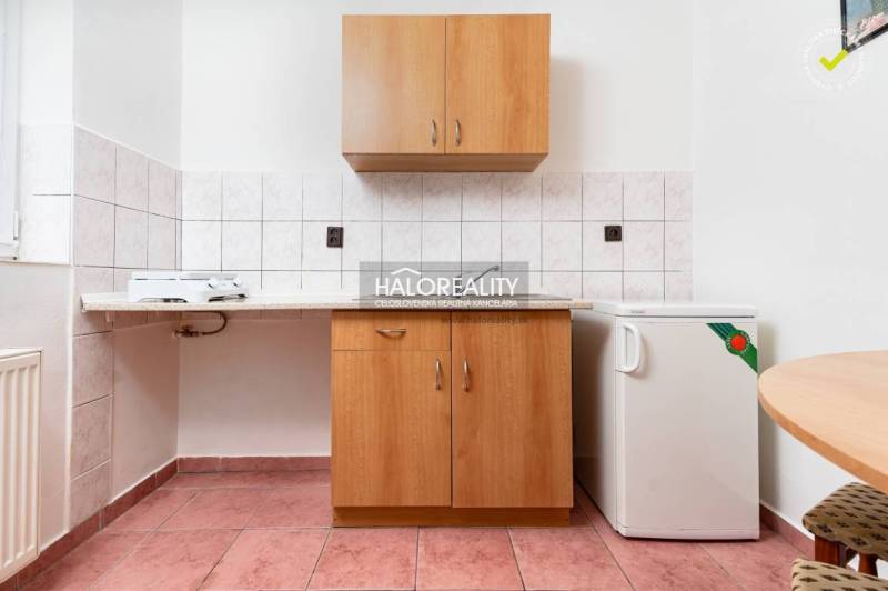 Kitchen area with tiles, cabinets, and a small refrigerator in hotels and guesthouses.