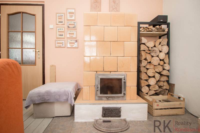 Brick fireplace with wood, door, and ottoman in the interior of a family house.