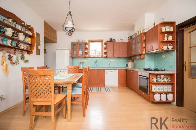 A kitchen in a family house with light furniture, ceramics, and a floor with a wooden decor.