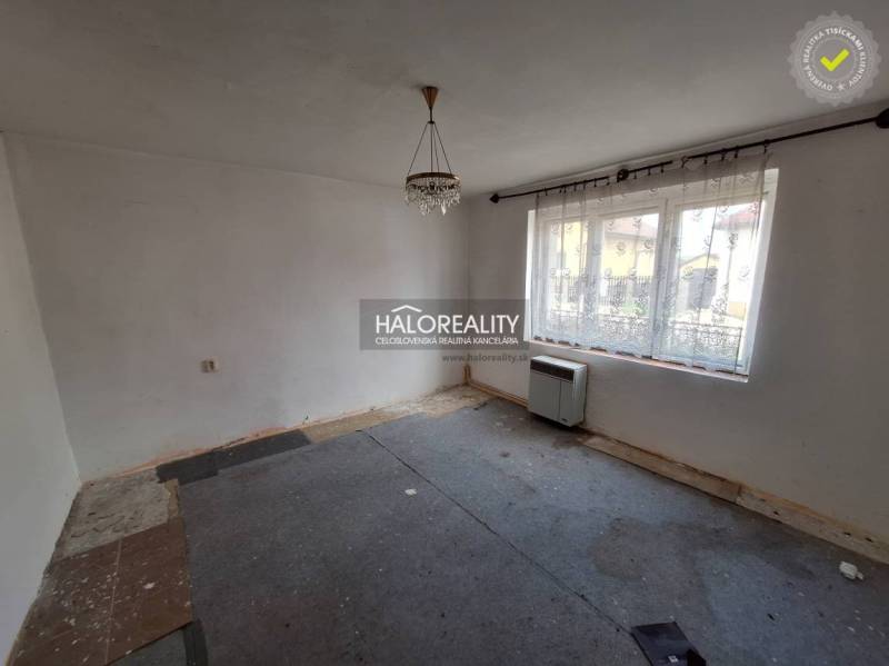 A room with a carpet, white walls, and a large window, suitable for renovation; Residential land.