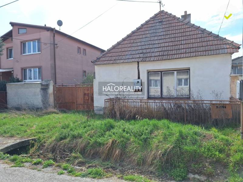 A house on a residential plot in the village of Dvorníky with a grassy garden and a fence.