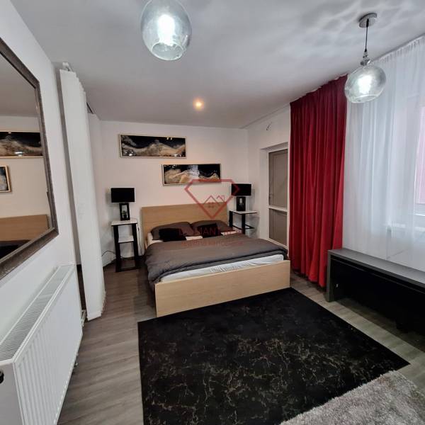 A bedroom in a family house with a mirror, red curtains, and wall decorations.