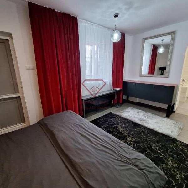 The interior of a family house with red curtains, a mirror, and a dark carpet.