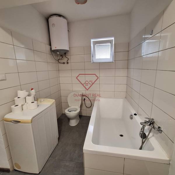 Bathroom in a family house with a bathtub, washing machine, boiler, and toilet.