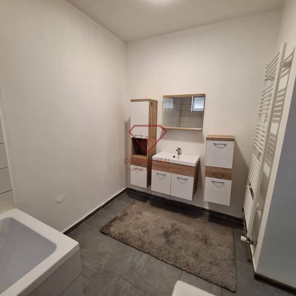 A bathroom in a family house with white furniture and dark tiles.