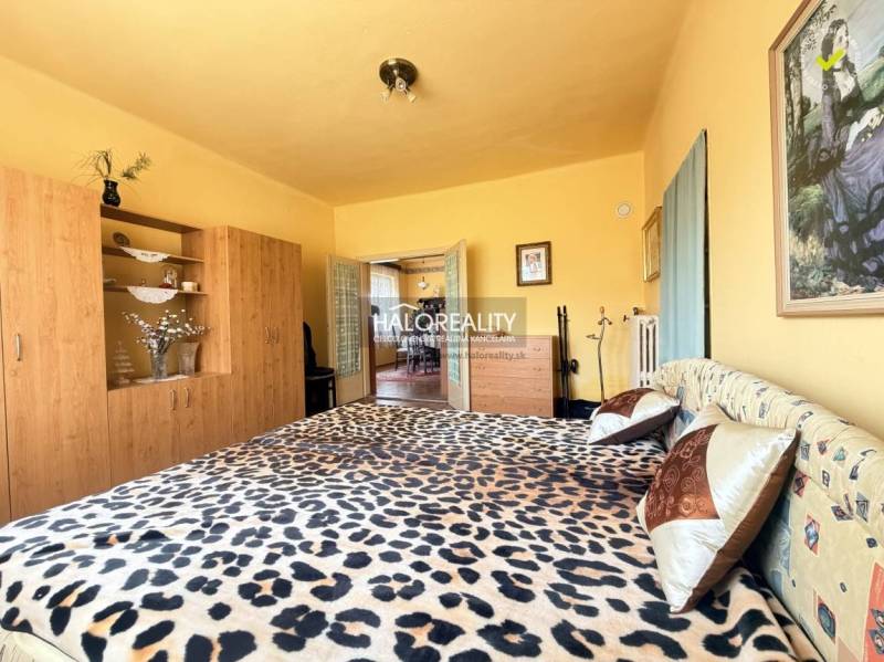 A bedroom in a family house with a bed featuring a leopard pattern and a wardrobe with a wood decor.