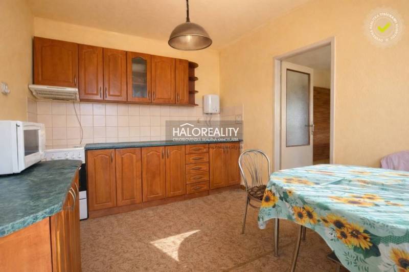 A kitchen in a family house with built-in cabinets and a table with a floral tablecloth.