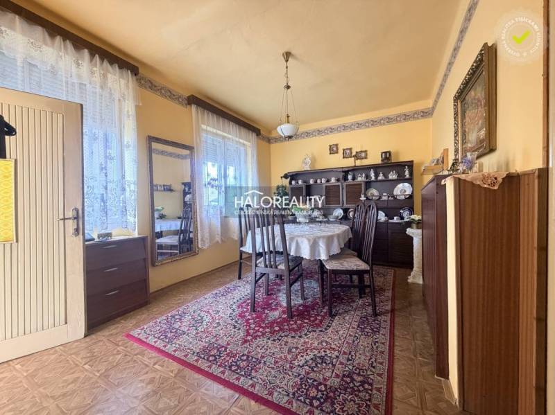 Dining room in a family house with a wooden decor floor, decorated carpet, and a table.