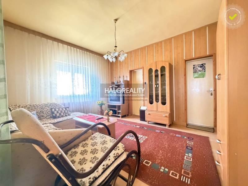 Living room in a family house with light from the window, wooden wall decor, and furniture.