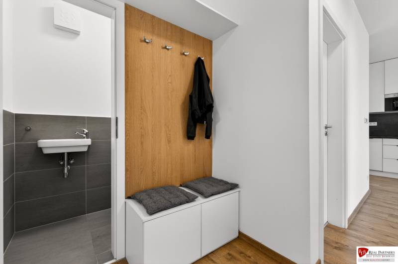 Entrance hall in a 2-room apartment with a bench, coat hooks, and a sink, floor with wood decor.