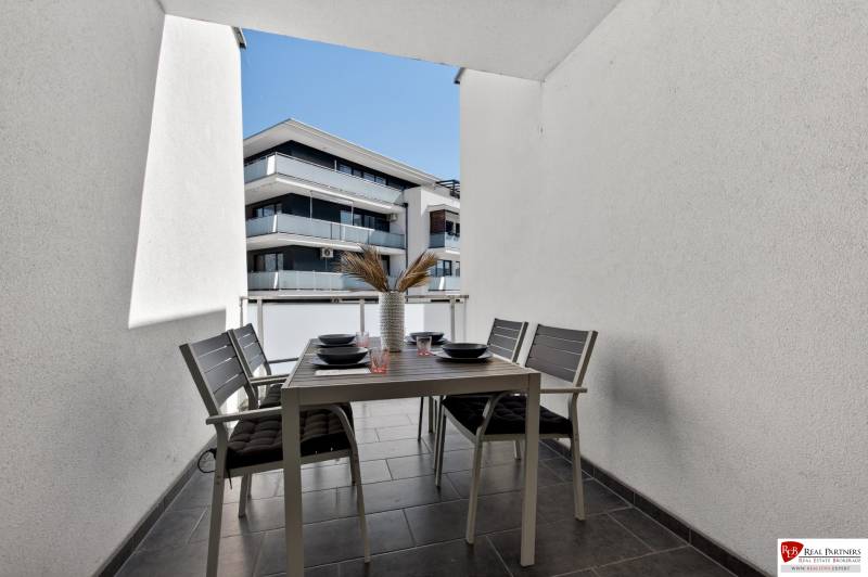 The balcony of a 2-room apartment on Orechova Street in Dunajska Luzna with an outdoor table and chairs.