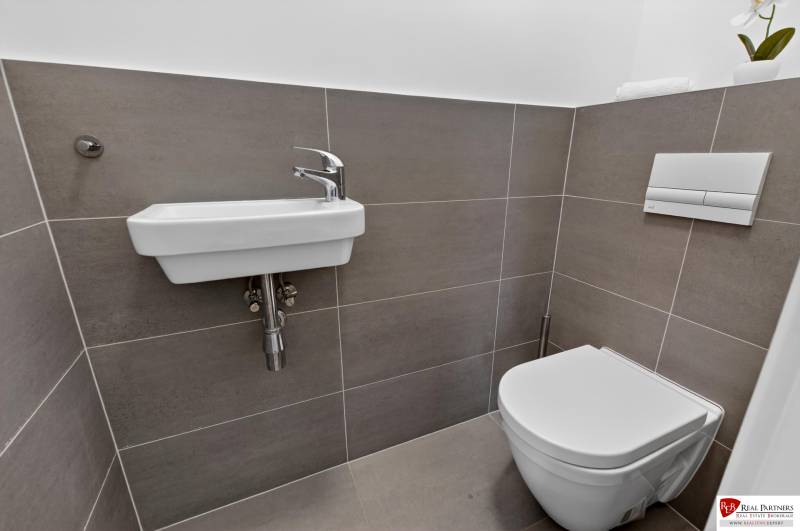 Bathroom with a sink and toilet in a 2-room apartment with simple tiles.