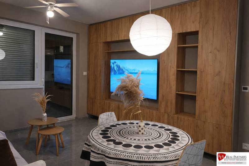Living room in a two-room apartment with a wooden decor floor and a round table.