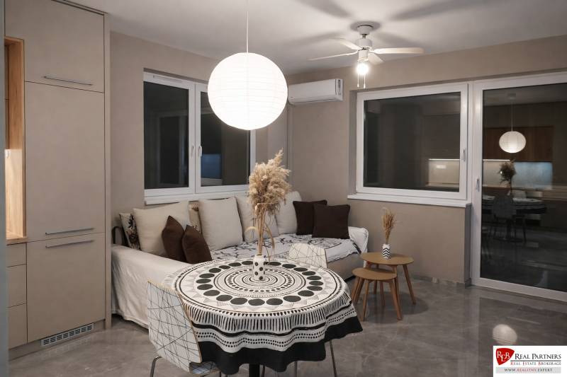 Living room with a sofa, round table, and decorative light fixture in a 2-room apartment.