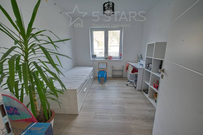 Children's room in a family house with a bed, table, and shelf on a floor with a wooden decor.