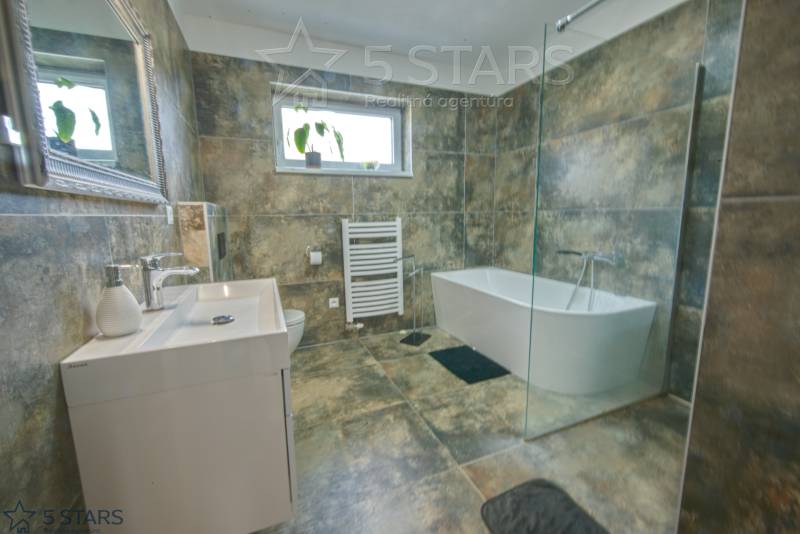 A bathroom with a glass shower enclosure and a bathtub in a family house.