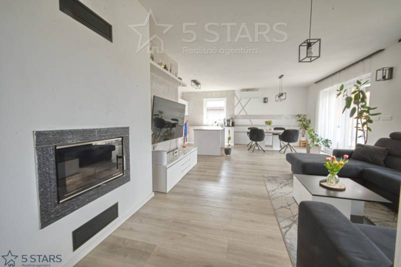 Living room with a fireplace, TV, and wood-patterned flooring in a family house.