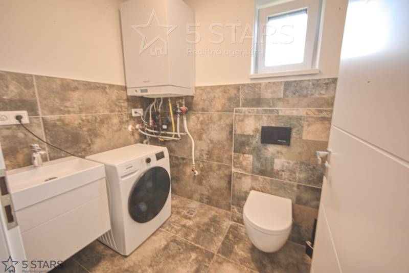 Bathroom in a family house with a sink, washing machine, and toilet.