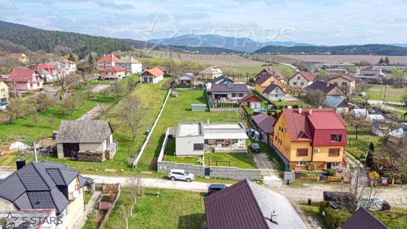 Family houses on Bošianska Street in Neporadza surrounded by greenery and mountains.