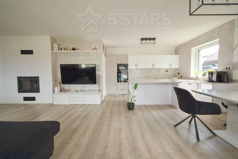 Living room with kitchen in a family house, light walls, floor with wooden decor.