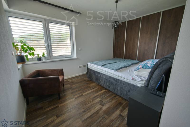 Bedroom in a family house with a bed, chair, and floor with wood decor.