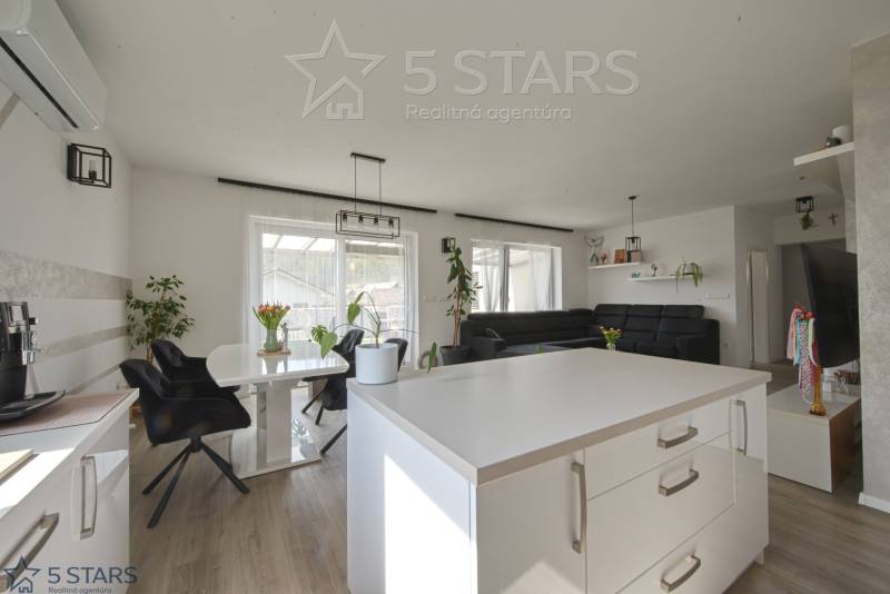 The interior of a family house with a wooden decor floor, white walls, and black furniture.