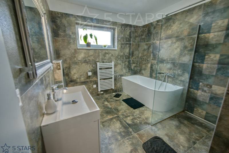 Bathroom with a bathtub, shower, and tiles in a family house.