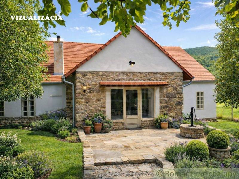 A family house in Dobroč with stone elements, surrounded by a well-maintained garden and trees.