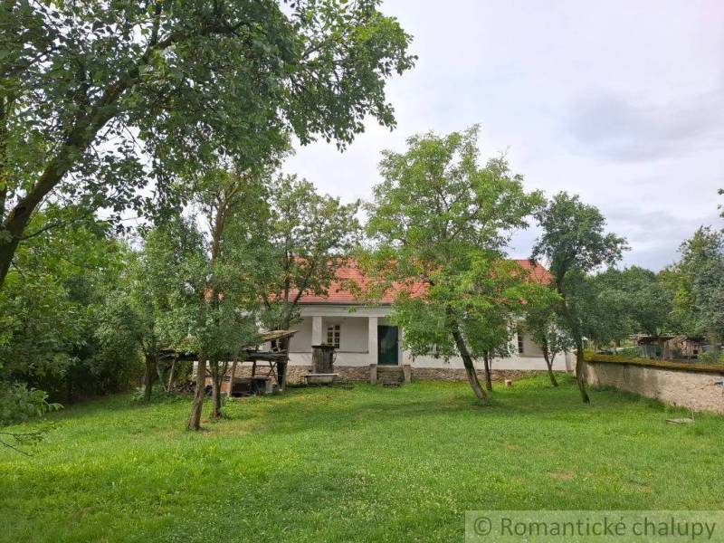 A family house in Dobroč with a white facade and a red roof, surrounded by greenery.