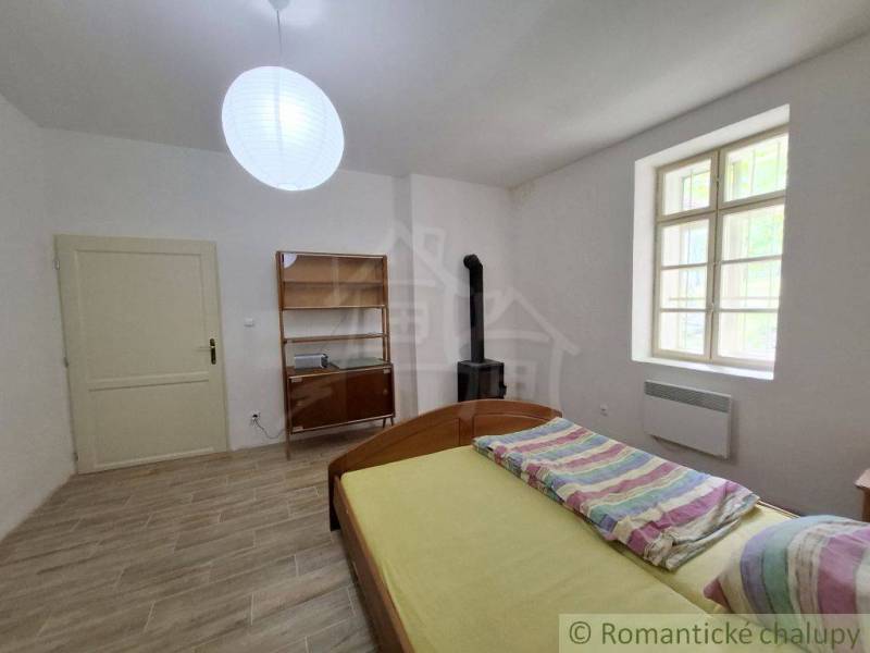 A room in a family house with a wooden decor floor, a bed, and a stove.